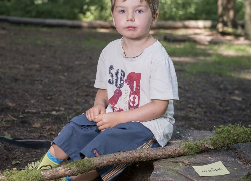 Un enfant qui a trouvé deux cartes avec des adjectifs contraires.
